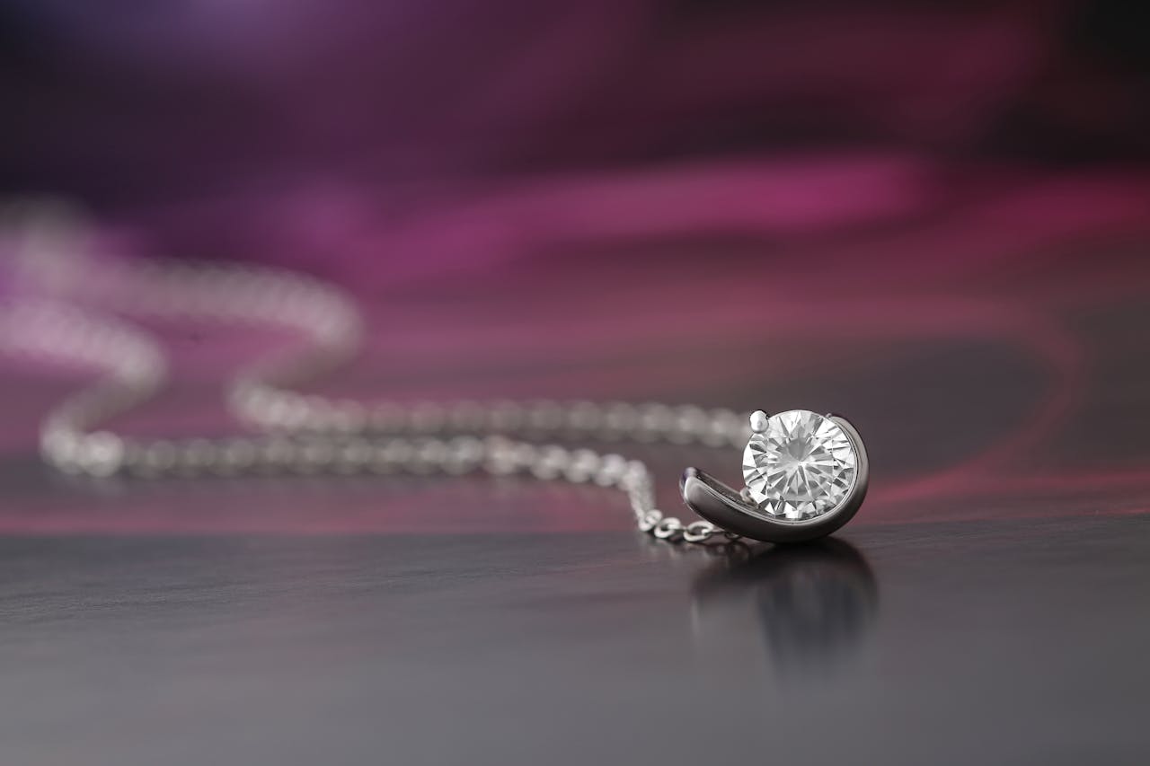 A close-up of a diamond necklace displayed against a soft, blurred background.